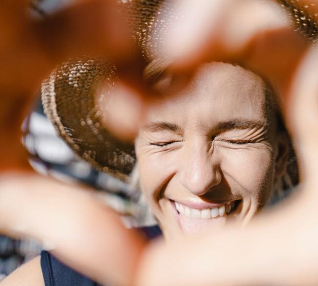 Woman smiling while making a heart with her hands