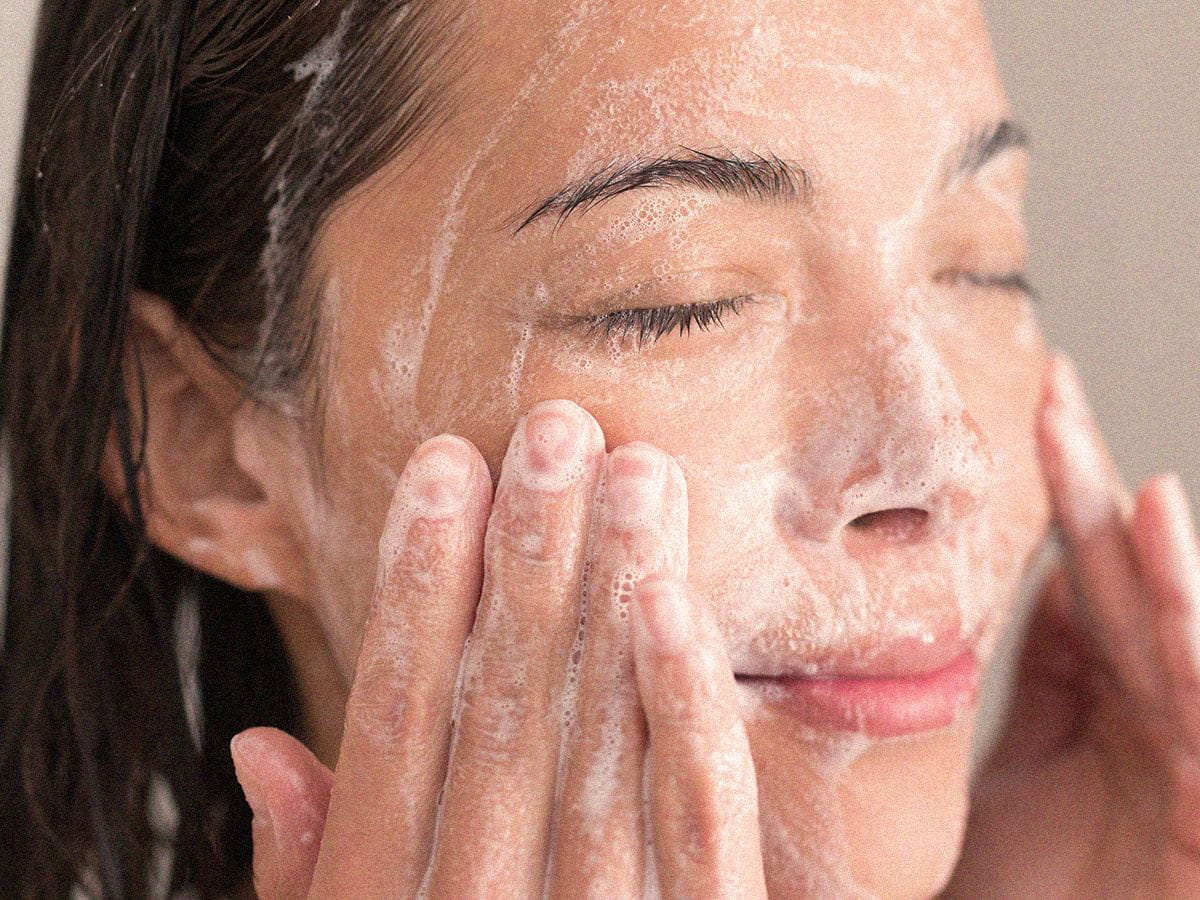 woman washing face with cleanser