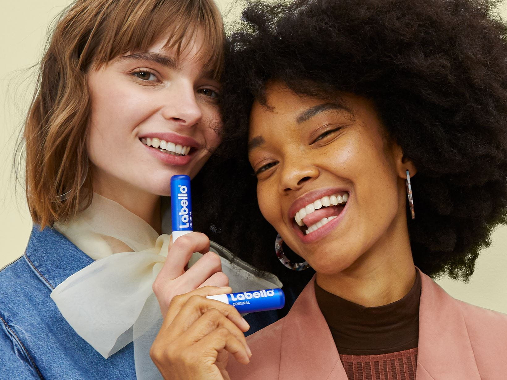 Zwei lächelnde Frauen mit dem Labello Original Lippenbalsam in ihren Händen.