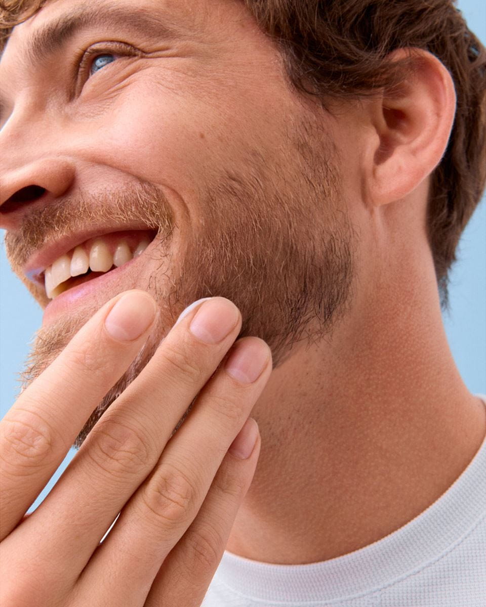 Close-up view of a person holding their chin while smiling.