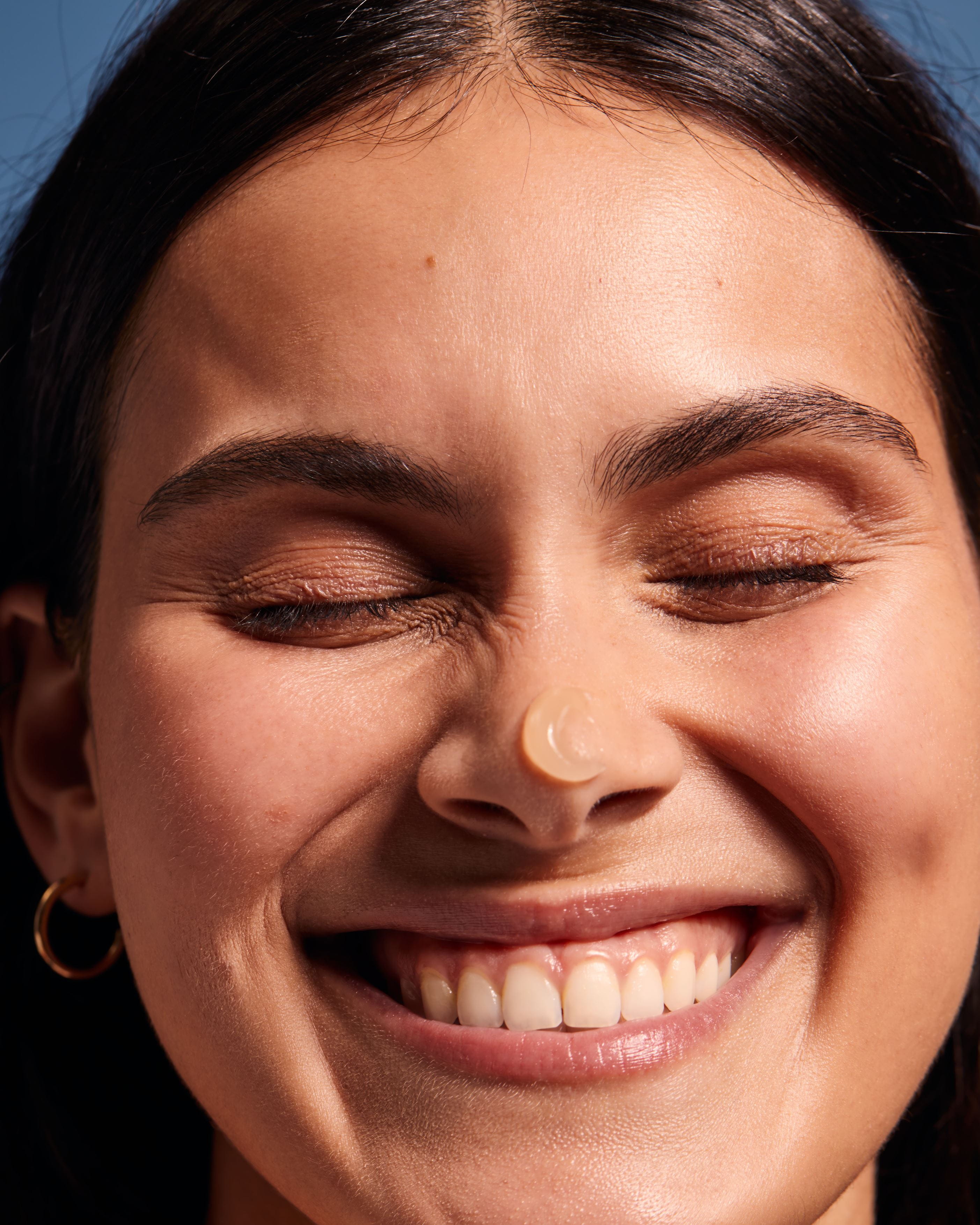 woman smiling with sunscreen on nose