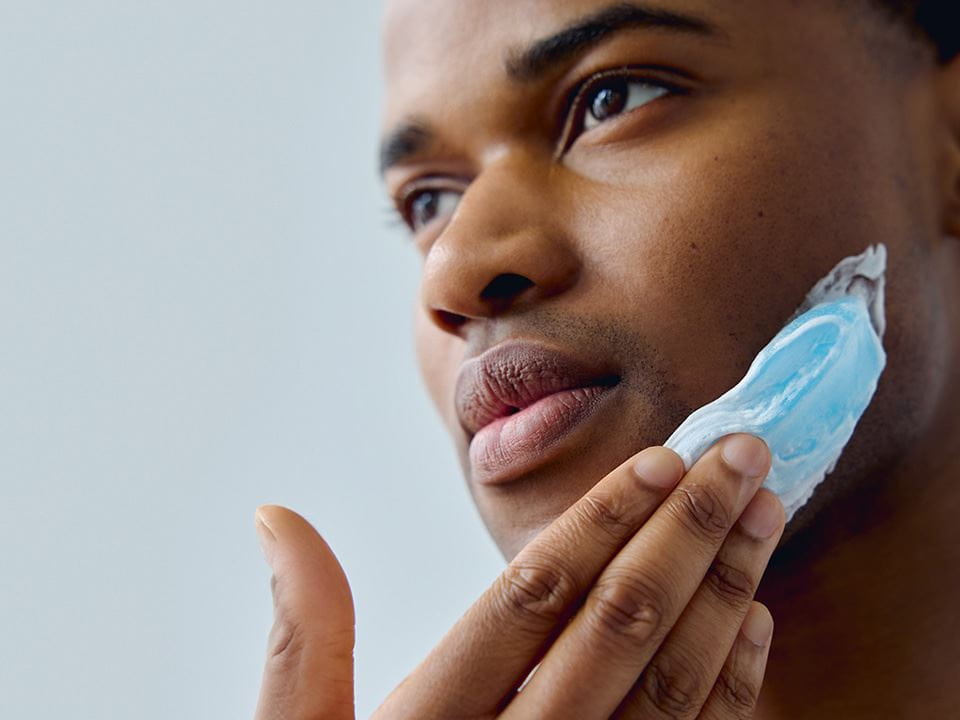 View of a person with a smudged Nivea product seen on the left side of their face.