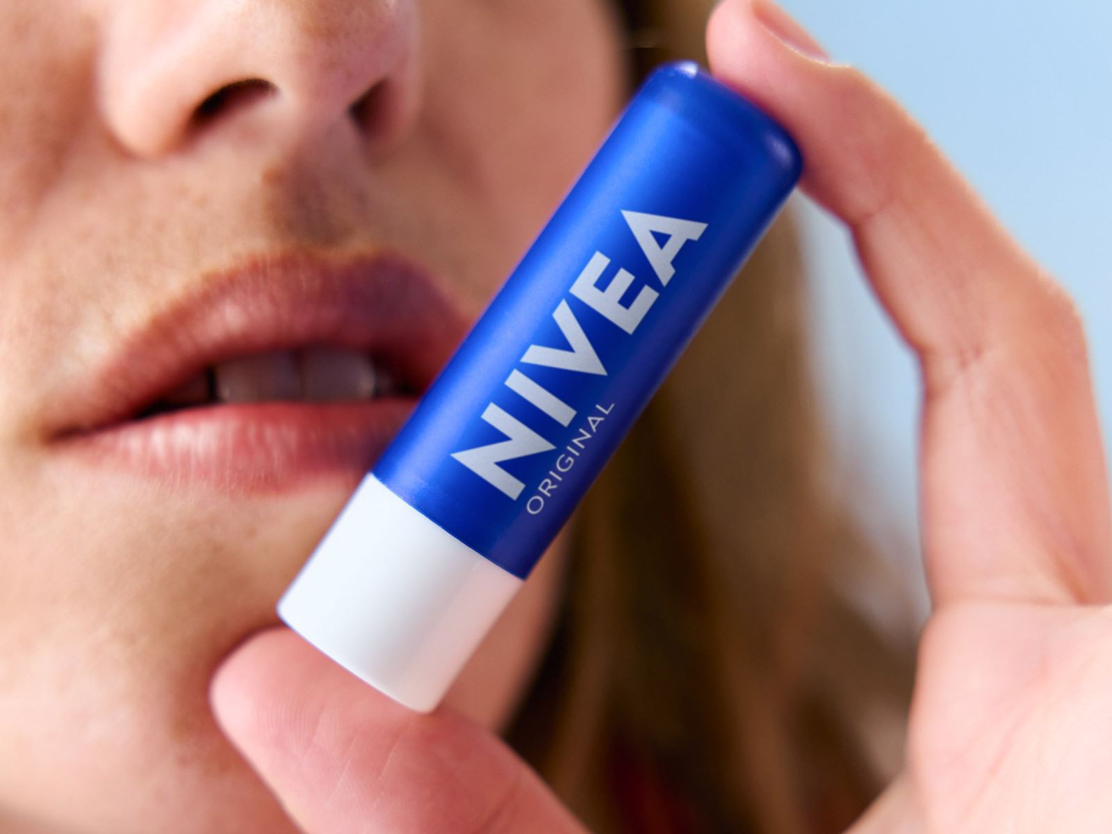 A close-up view of a NIVEA chapstick being held by a person close to their face.