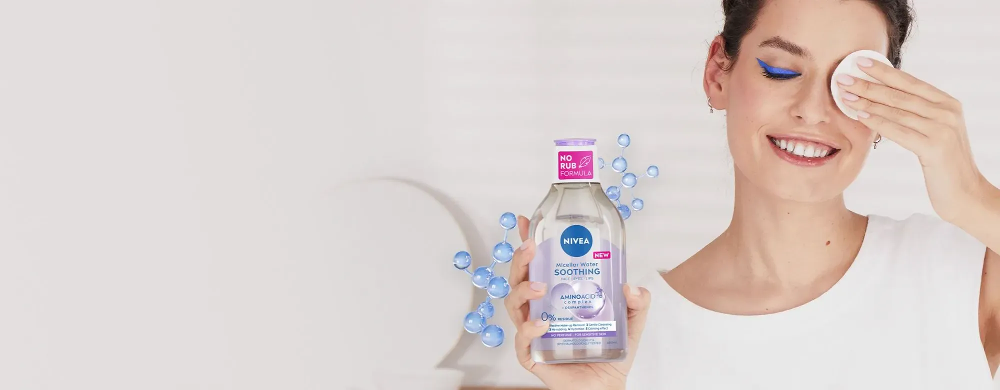 A woman has removed heavy blue eye make-up with the NEW NIVEA Micellar Water and shows the cotton pad.