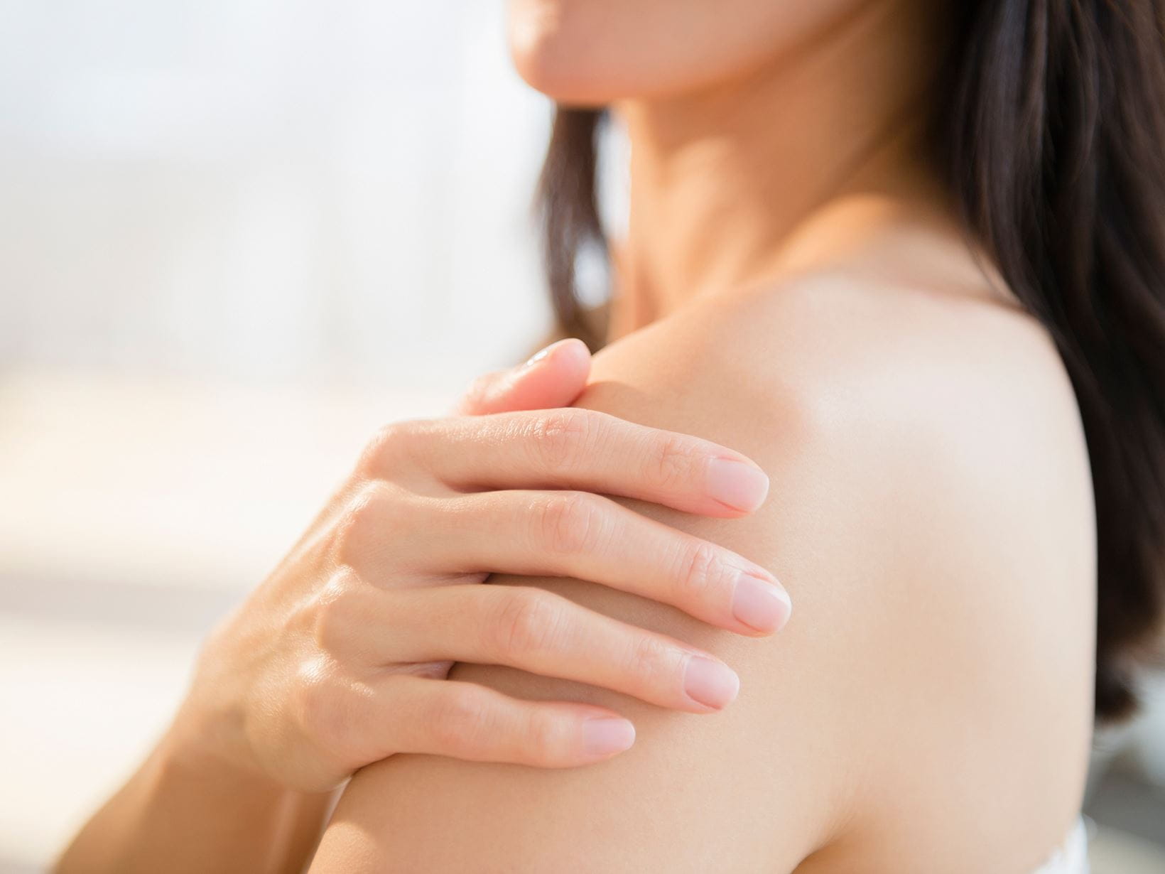 lady touching the dehydrated skin on her shoulder