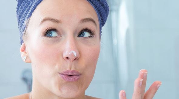 Femme avec serviette sur la tête et crème sur le nez