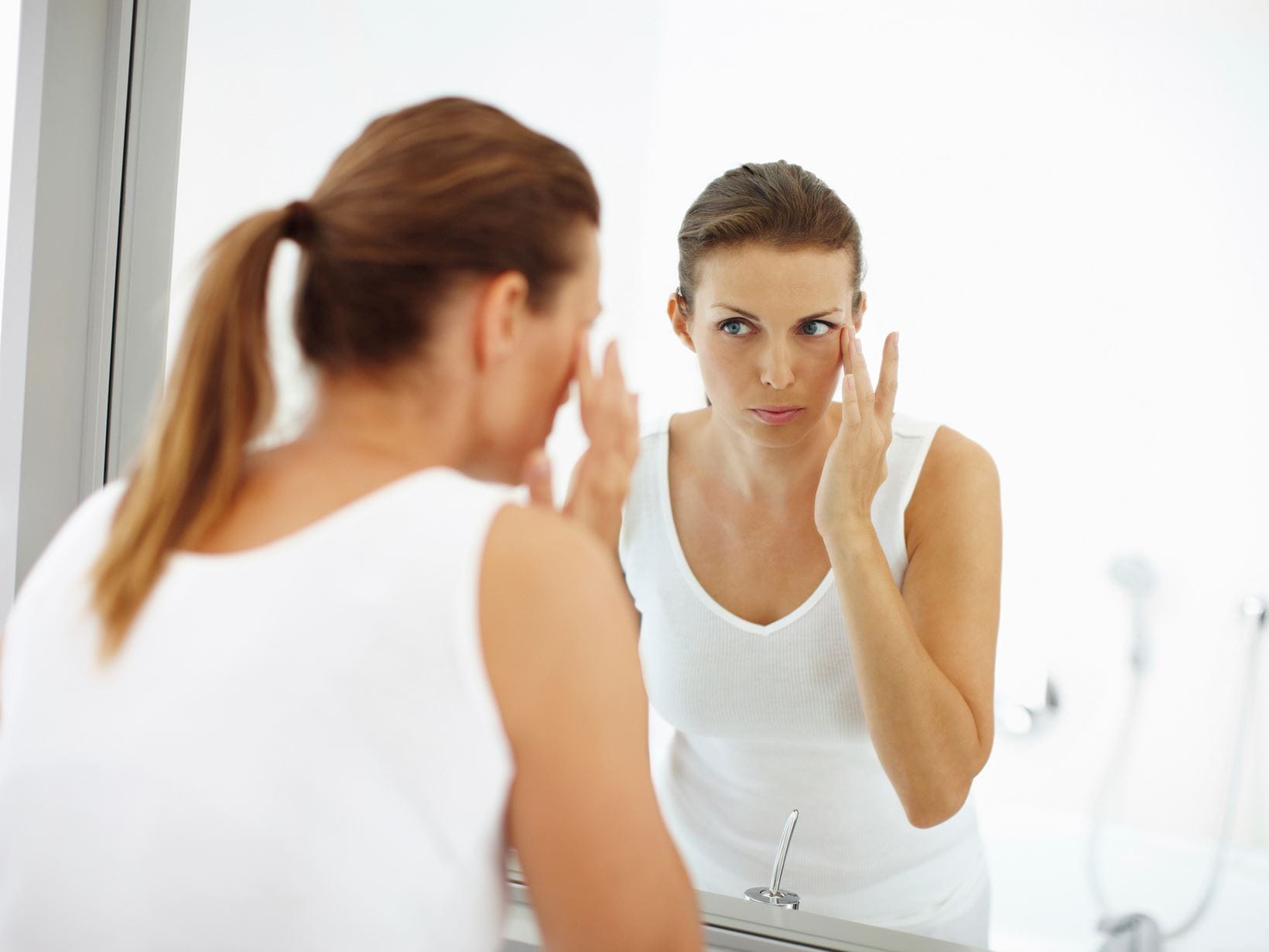 kobieta-stosująca-produkt-do-pielęgnacji-skóry-przed-lustrem-w-łazience