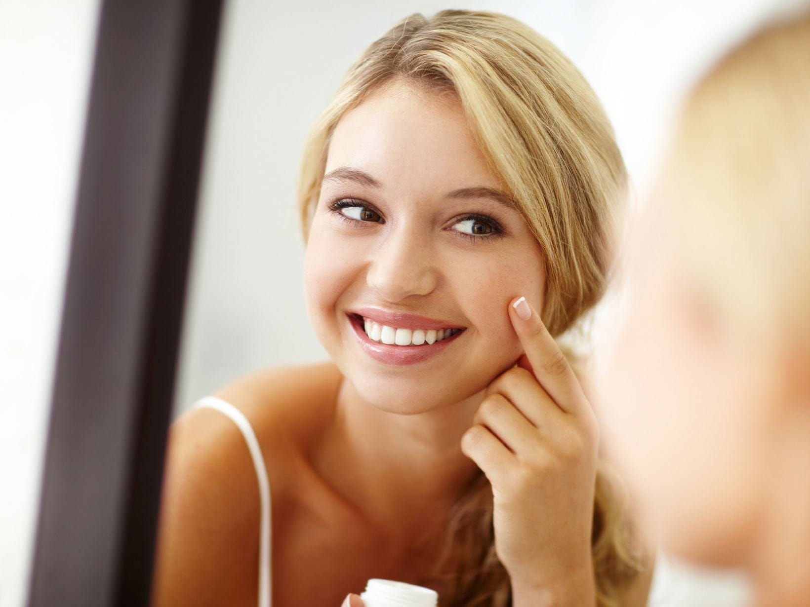 blonde lady smiling while using bb cream