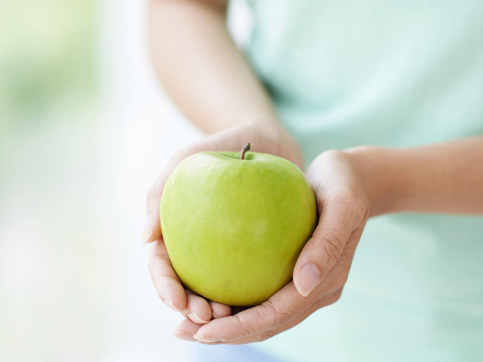 женщина-держит-в-руках-зеленое-яблоко