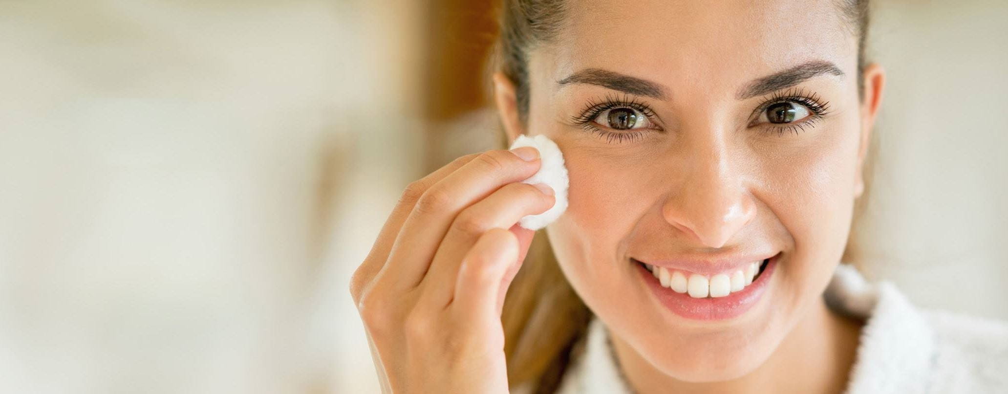 brunette lady using lactic acid skin on her face with a cotton pad