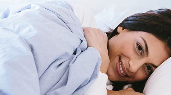 Vrouw in bed met blauwe lakens