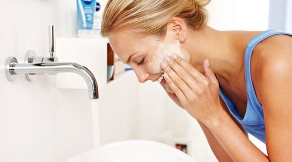 Blonde vrouw wast gezicht in badkamer