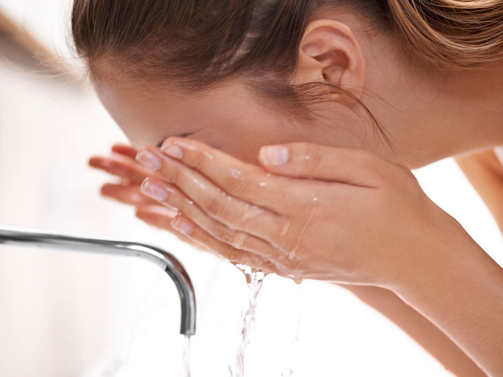 lady washing her face at the sink