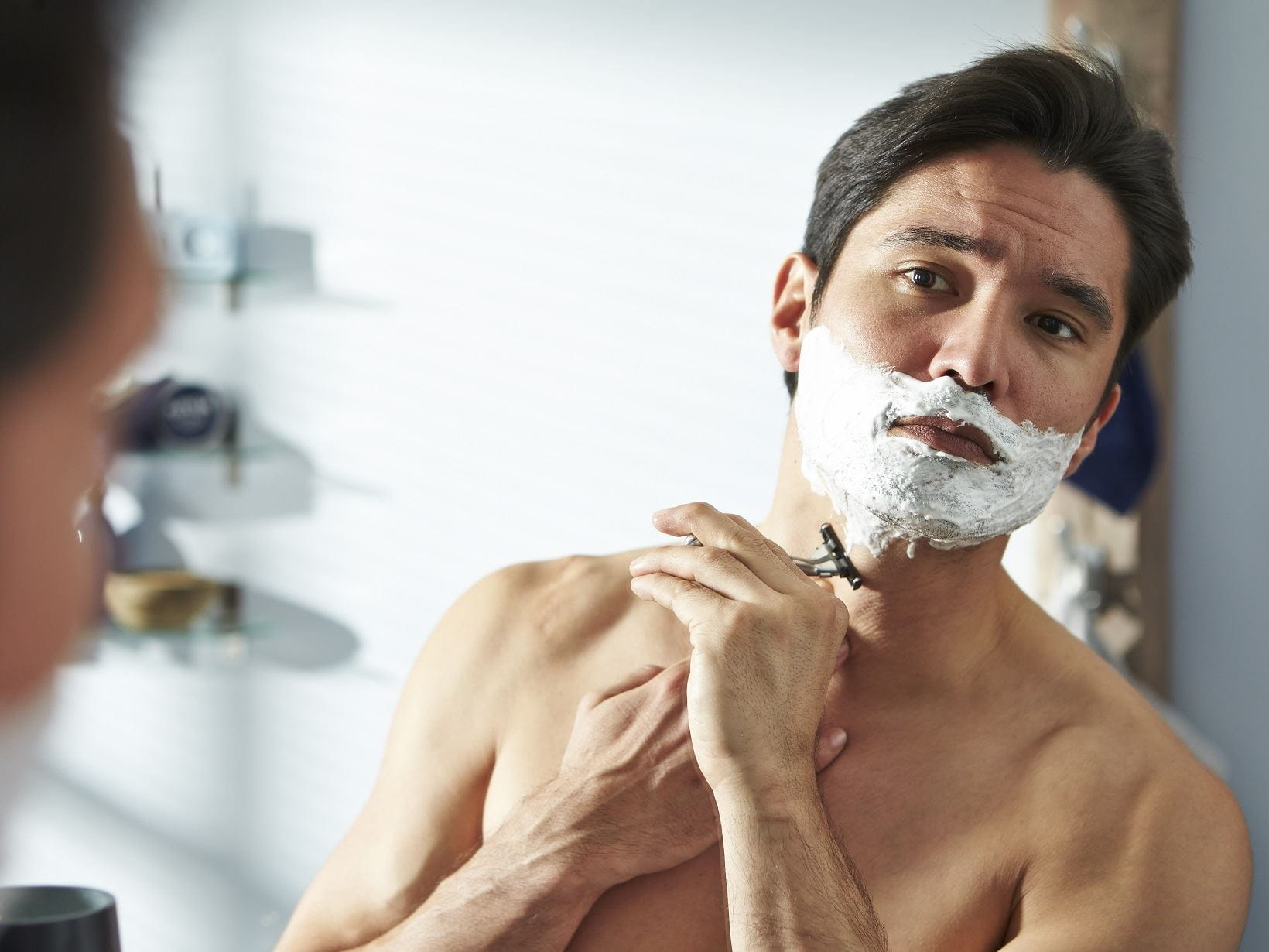 man shaping his beard in the mirror