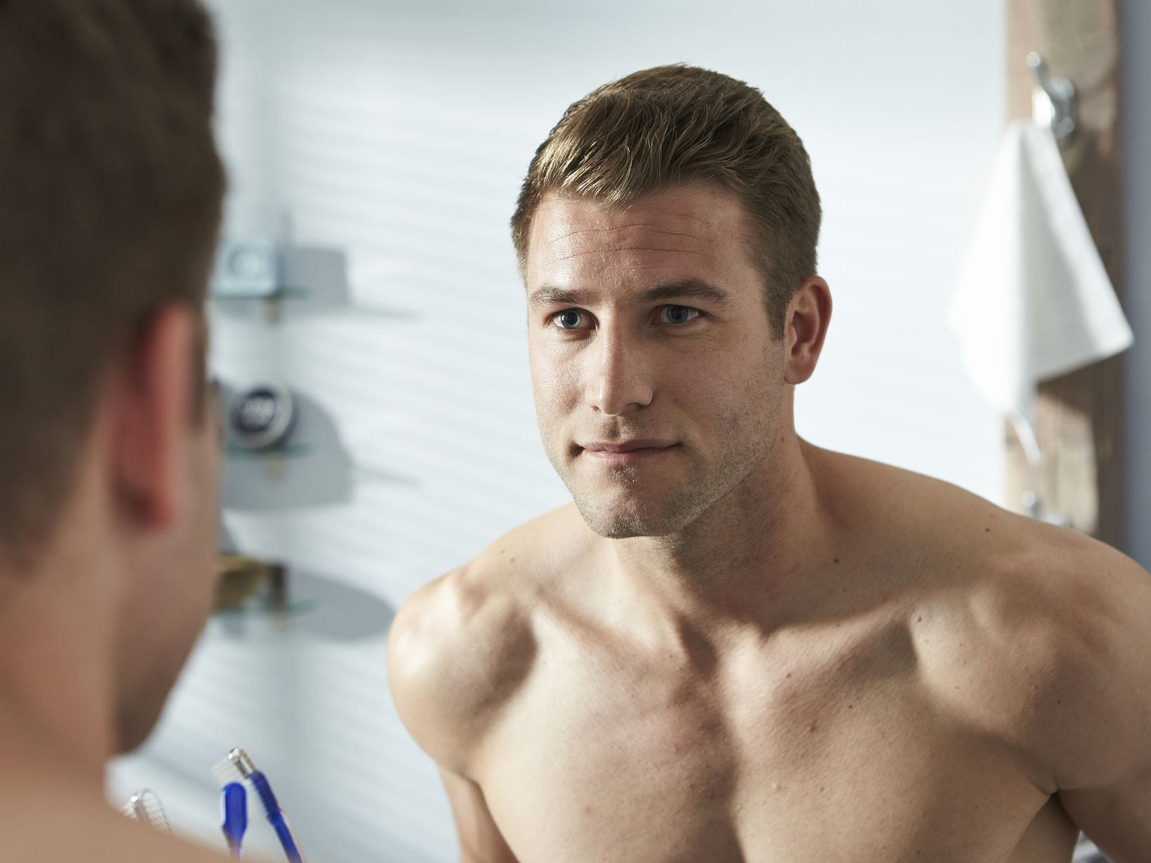 man with blonde hair looking at his reflection in the mirror