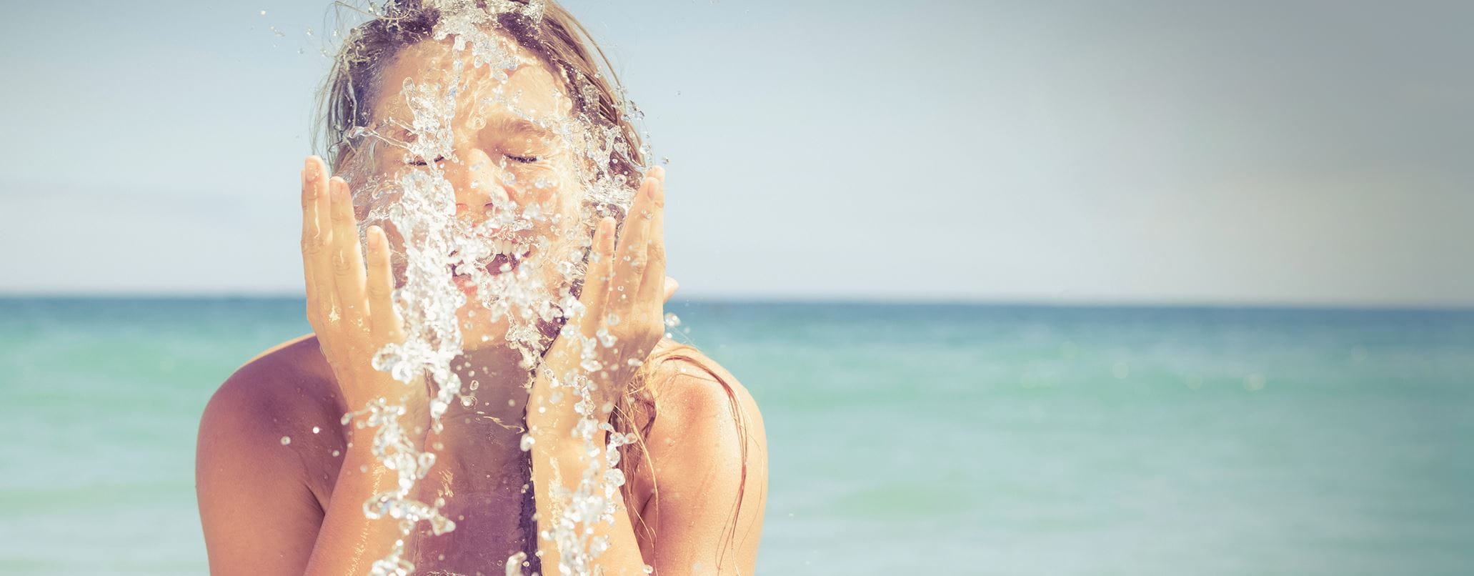 mulher a molhar o rosto na praia
