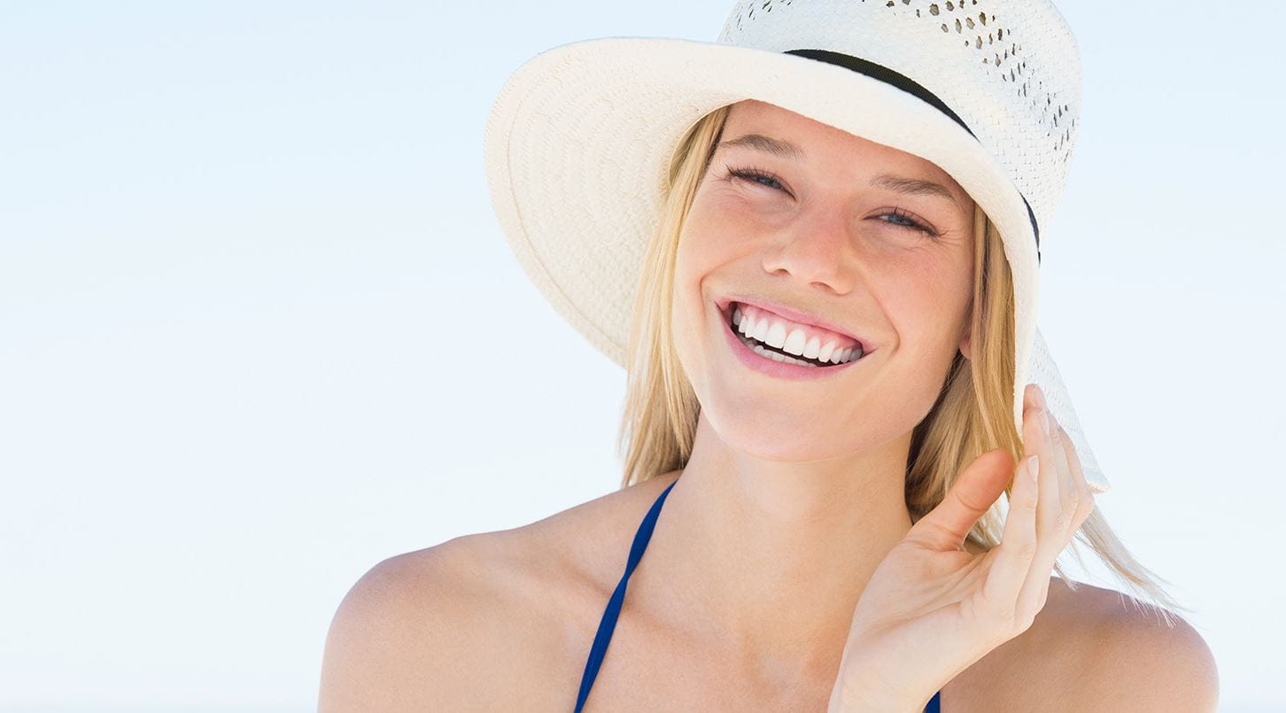 mulher com pele sensível a usar um chapéu na praia