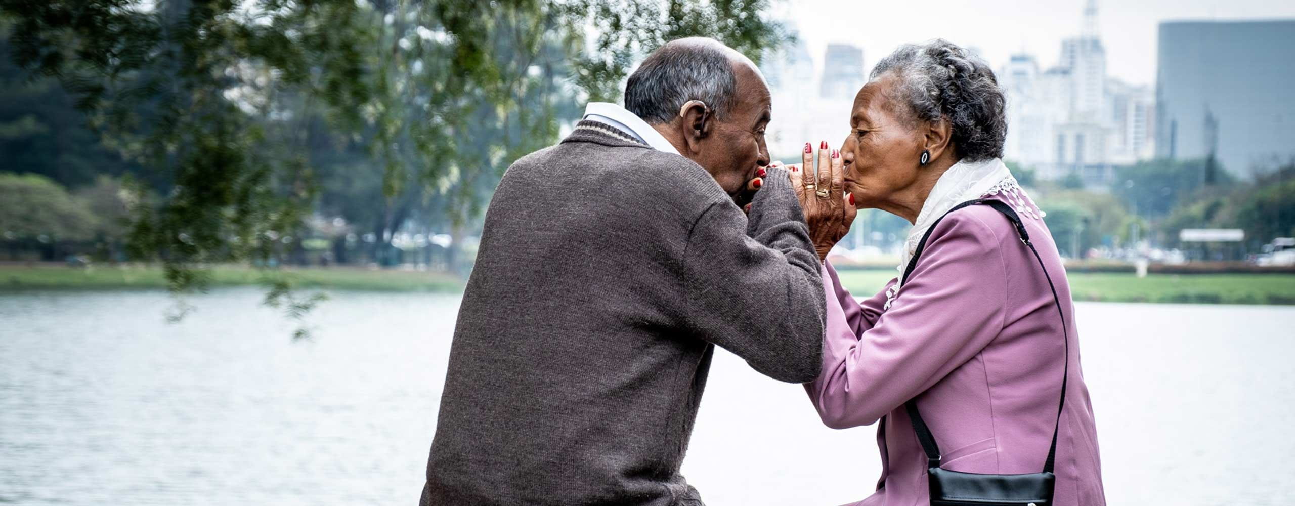 casal idoso de mãos dadas a dar um beijo