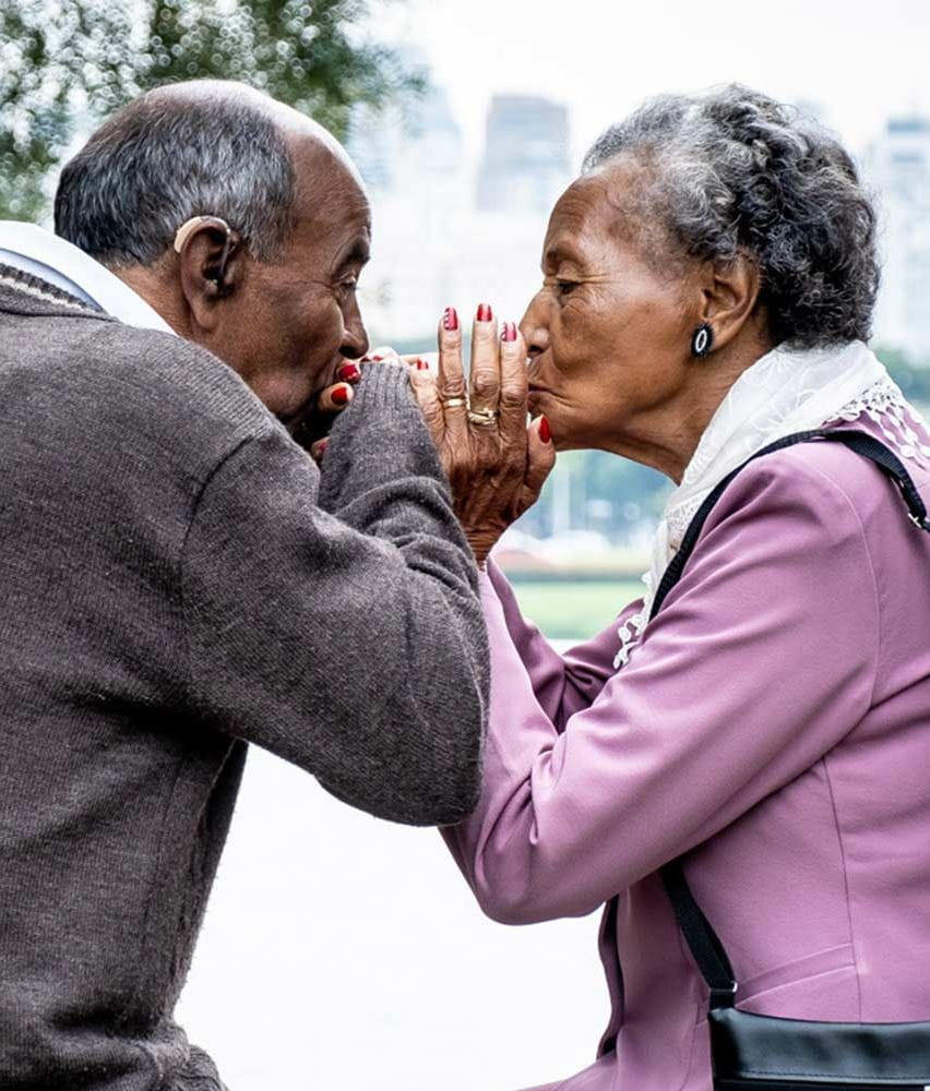 casal idoso de mãos dadas a dar um beijo