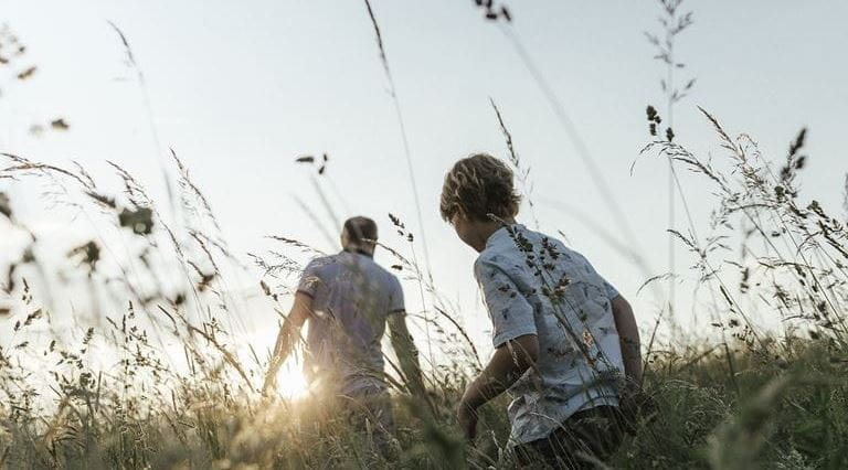 pai e filho a caminhar num campo com plantas secas