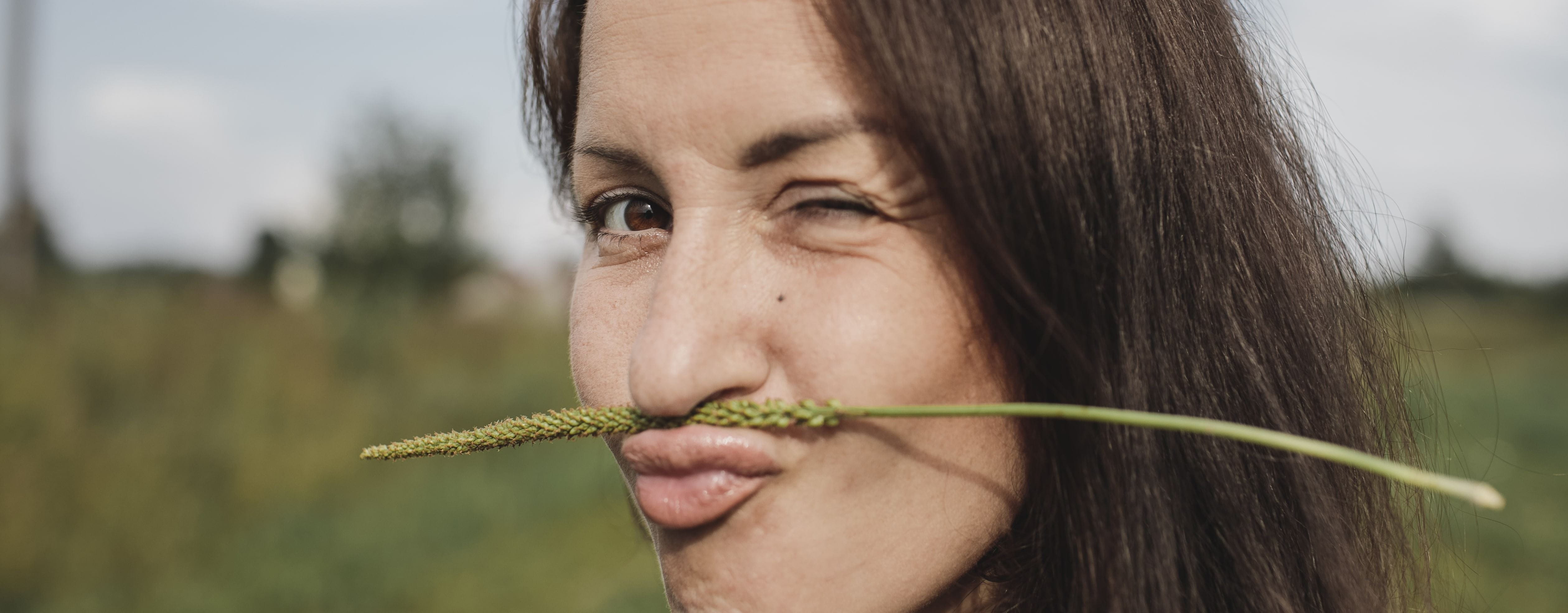 mulher com uma planta seca a fazer de bigode