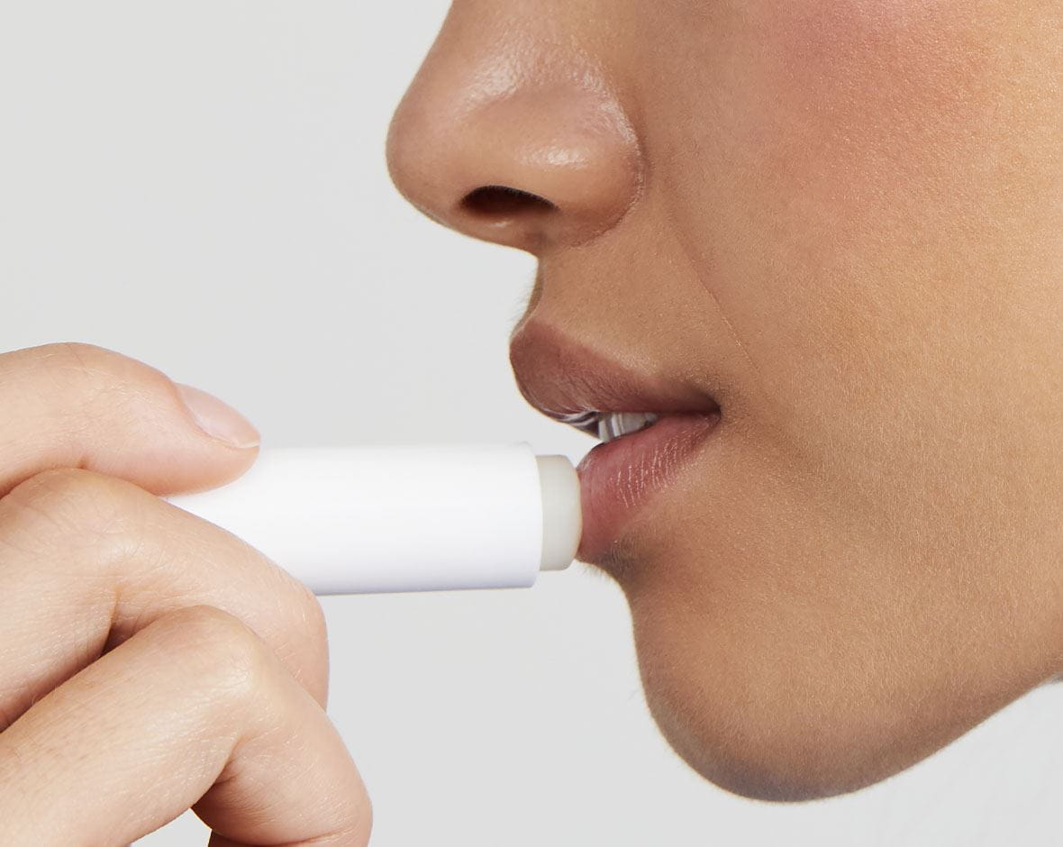 mujer aplicándose labial hidratante