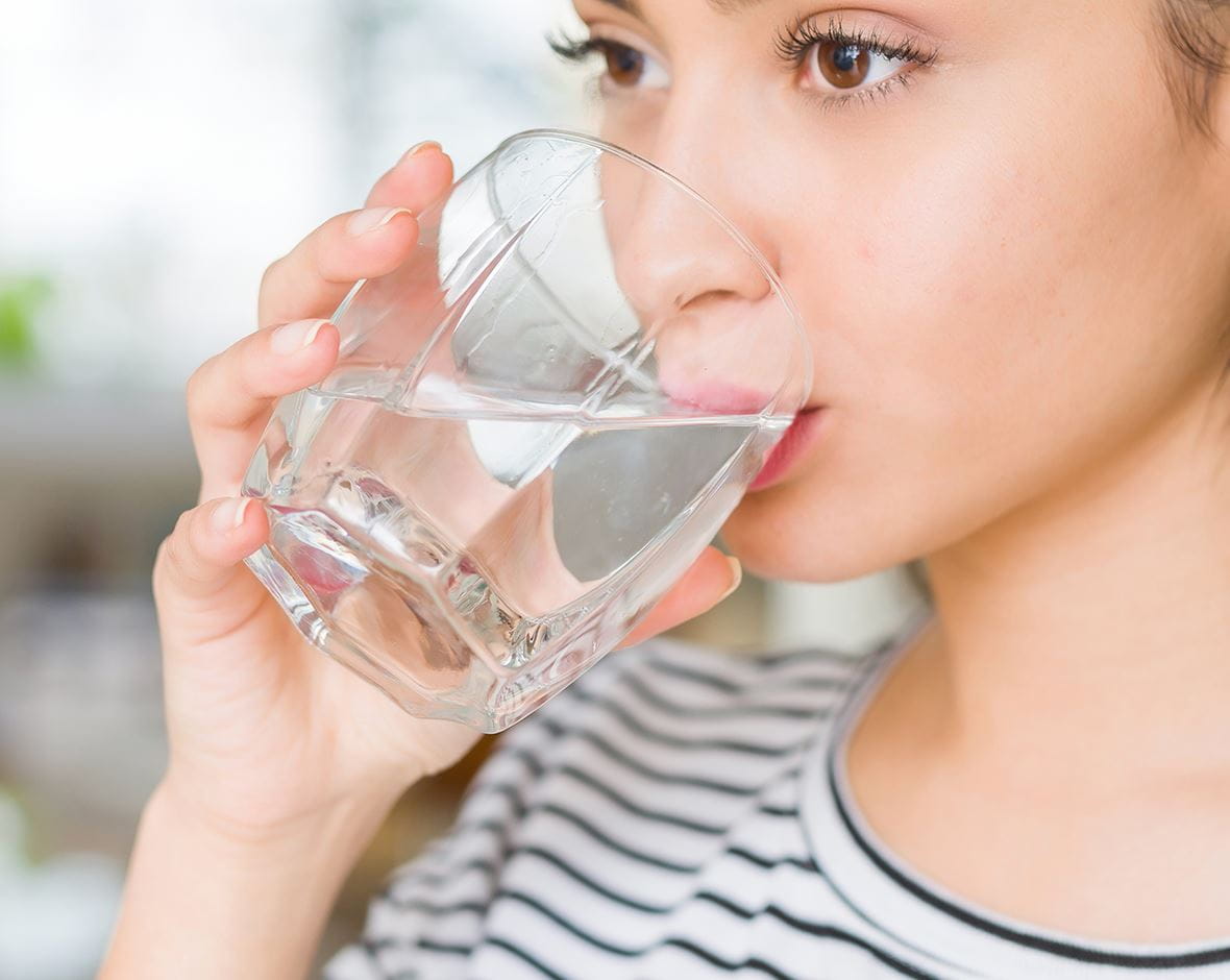 mujer hidratándose con agua