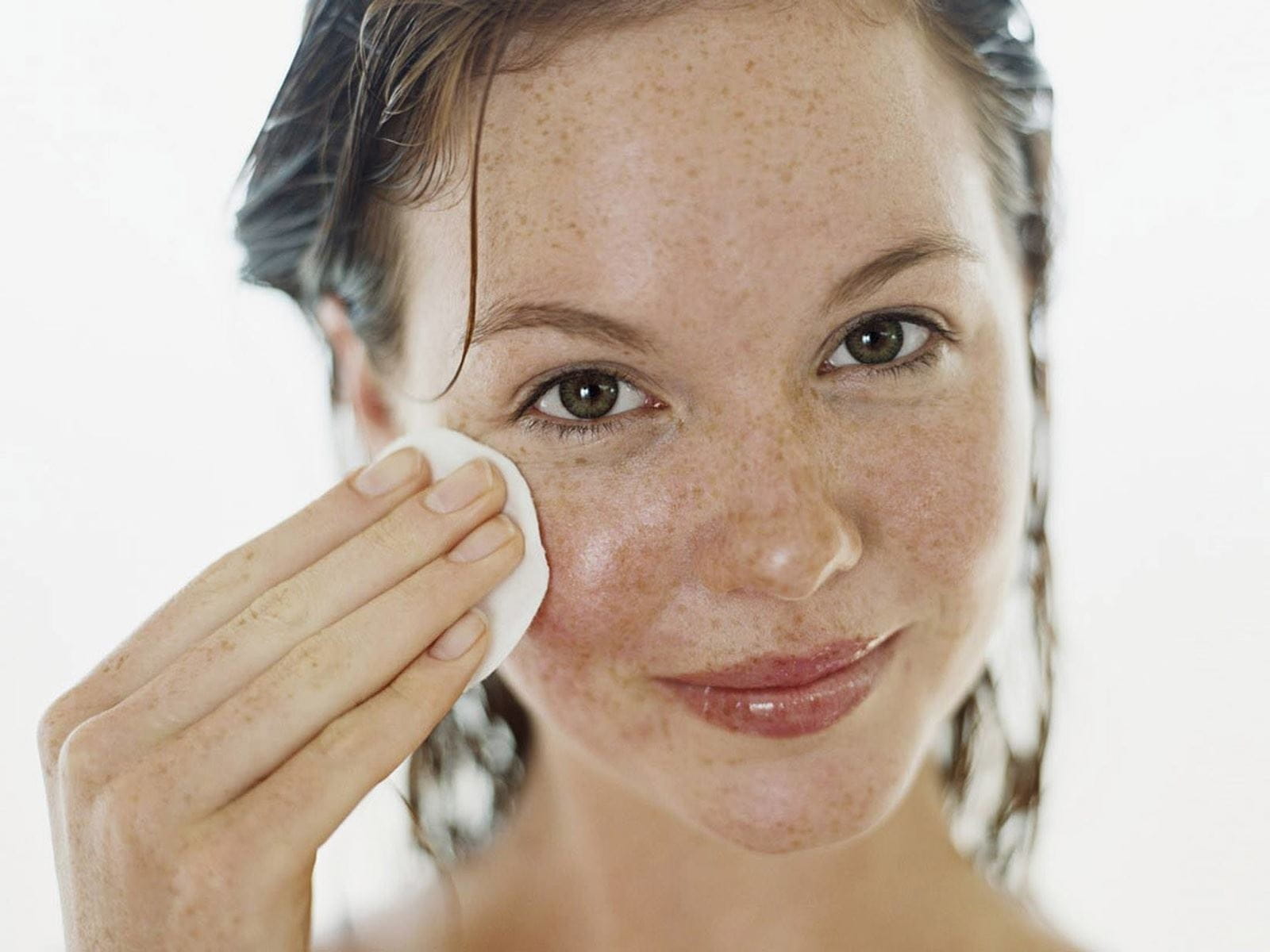 mujer haciendo limpieza facial con agua micelar