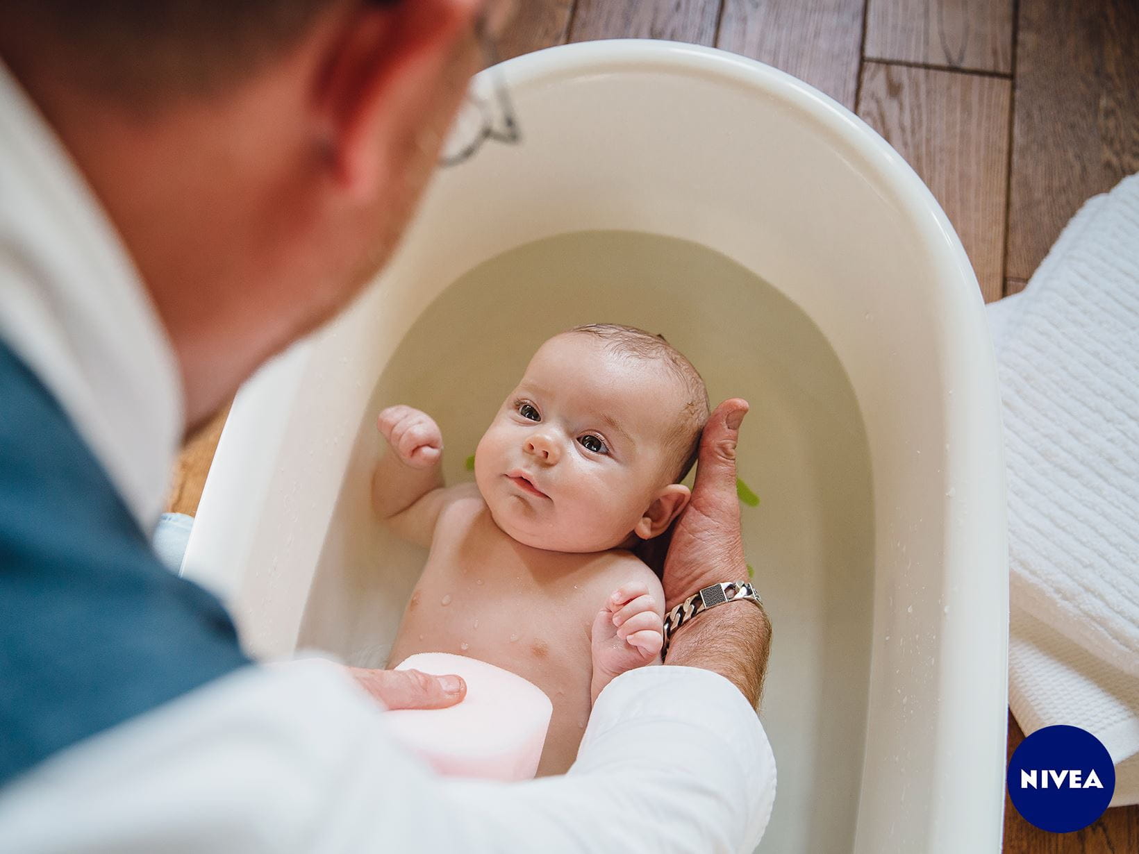 Ein Baby wird über eine Babybadewanne gehalten