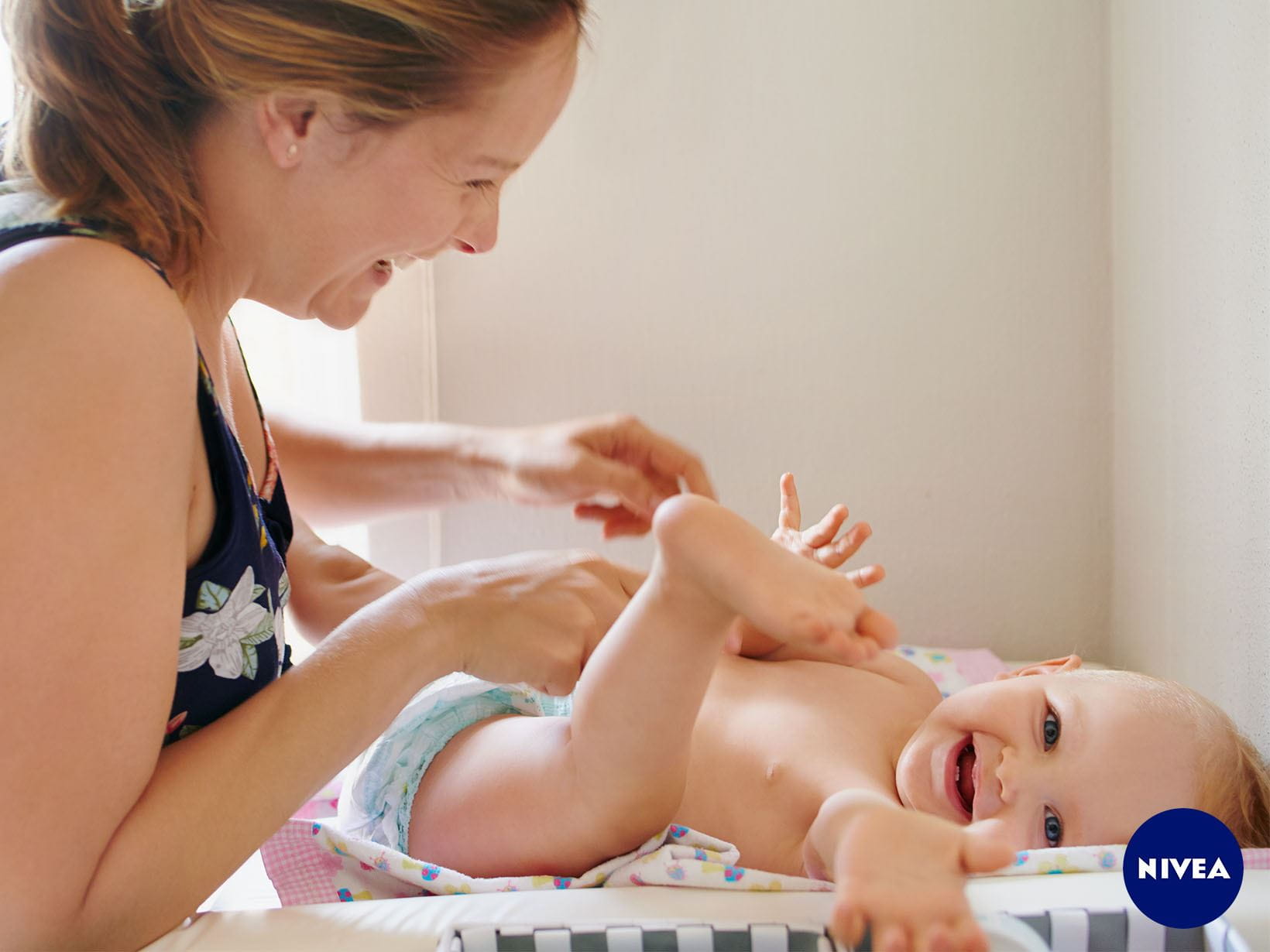 Eine Mutter wickelt ihr lachendes Baby