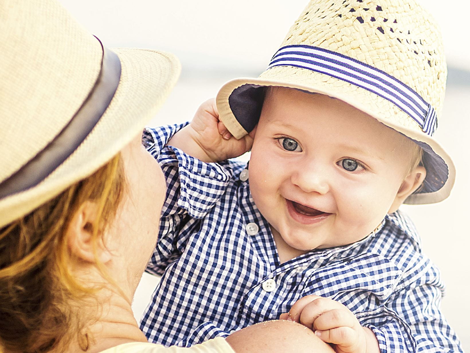 Ein Baby mit Hut auf dem Arm seiner Mutter