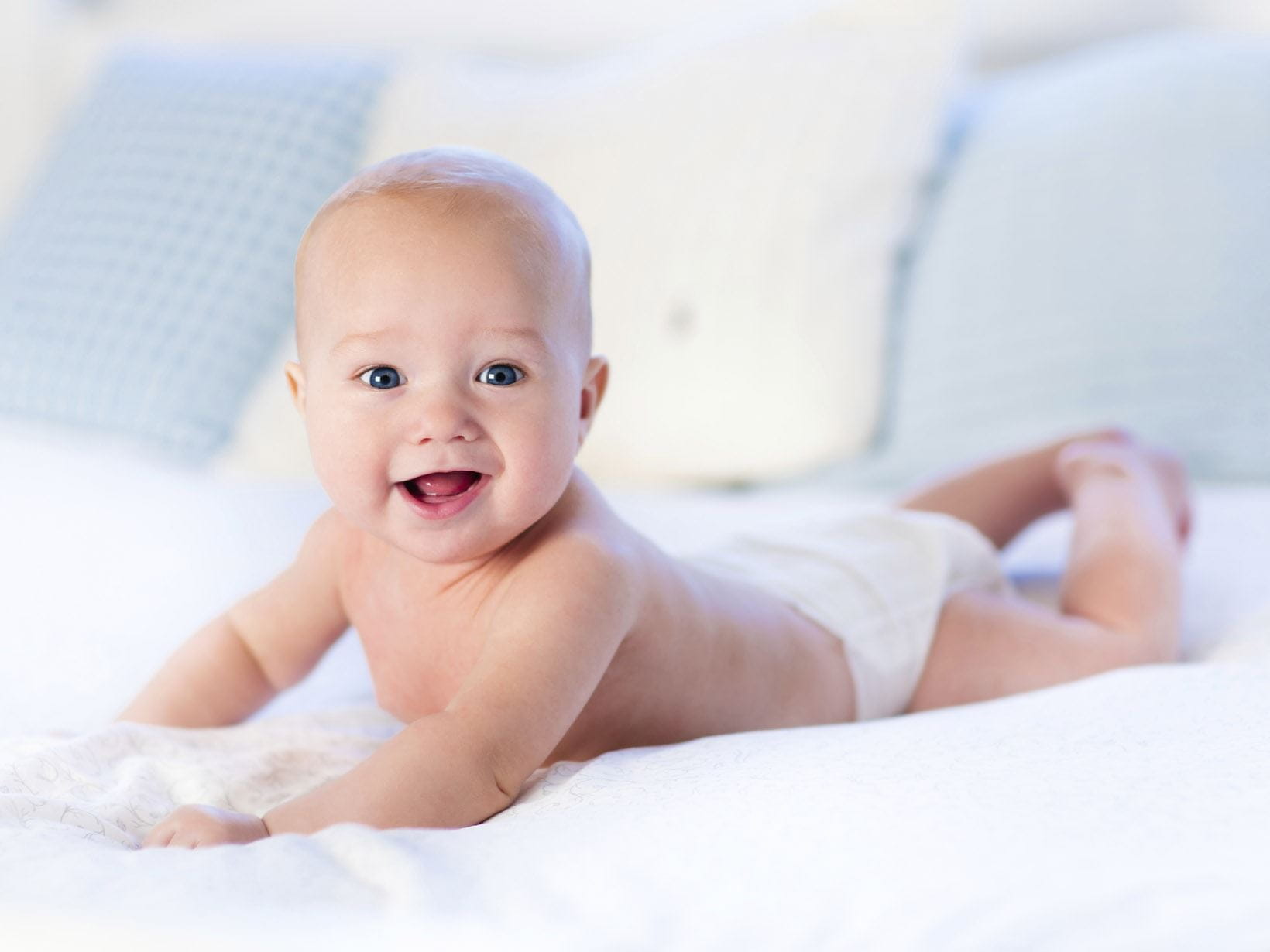 Ein lachendes Baby liegt auf dem Bauch