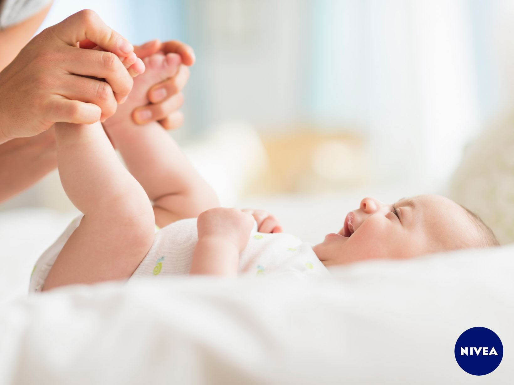 Eine Mutter hält die Füße ihres lachenden Babys