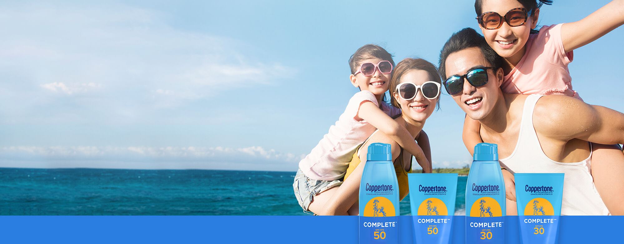 View of two children and two adult models wearing sunglasses and smiling with a body of water shown in the background and four Coppertone Complete Sunscreen products overlayed.