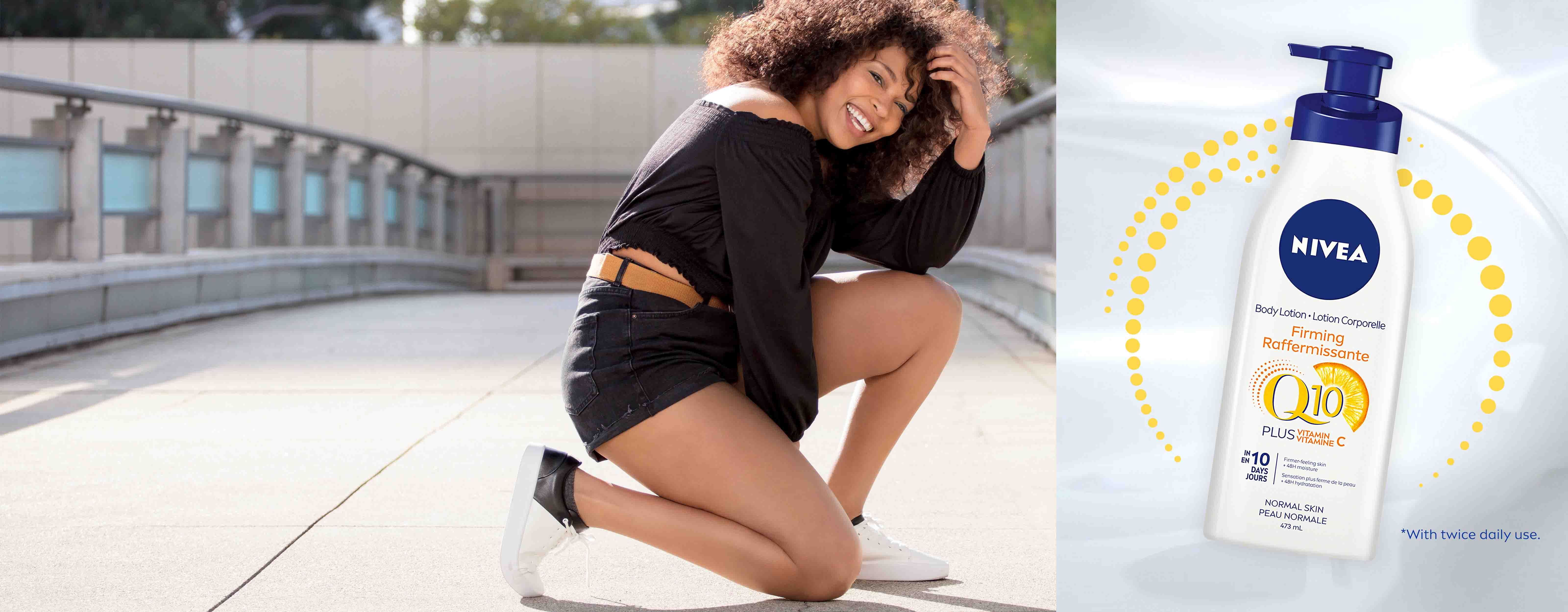 *with twice daily use. A view of a female model wearing dark-coloured clothing kneeling down on concrete with a Nivea Q10 Plus Vitamin C Body Lotion product shown to the right.