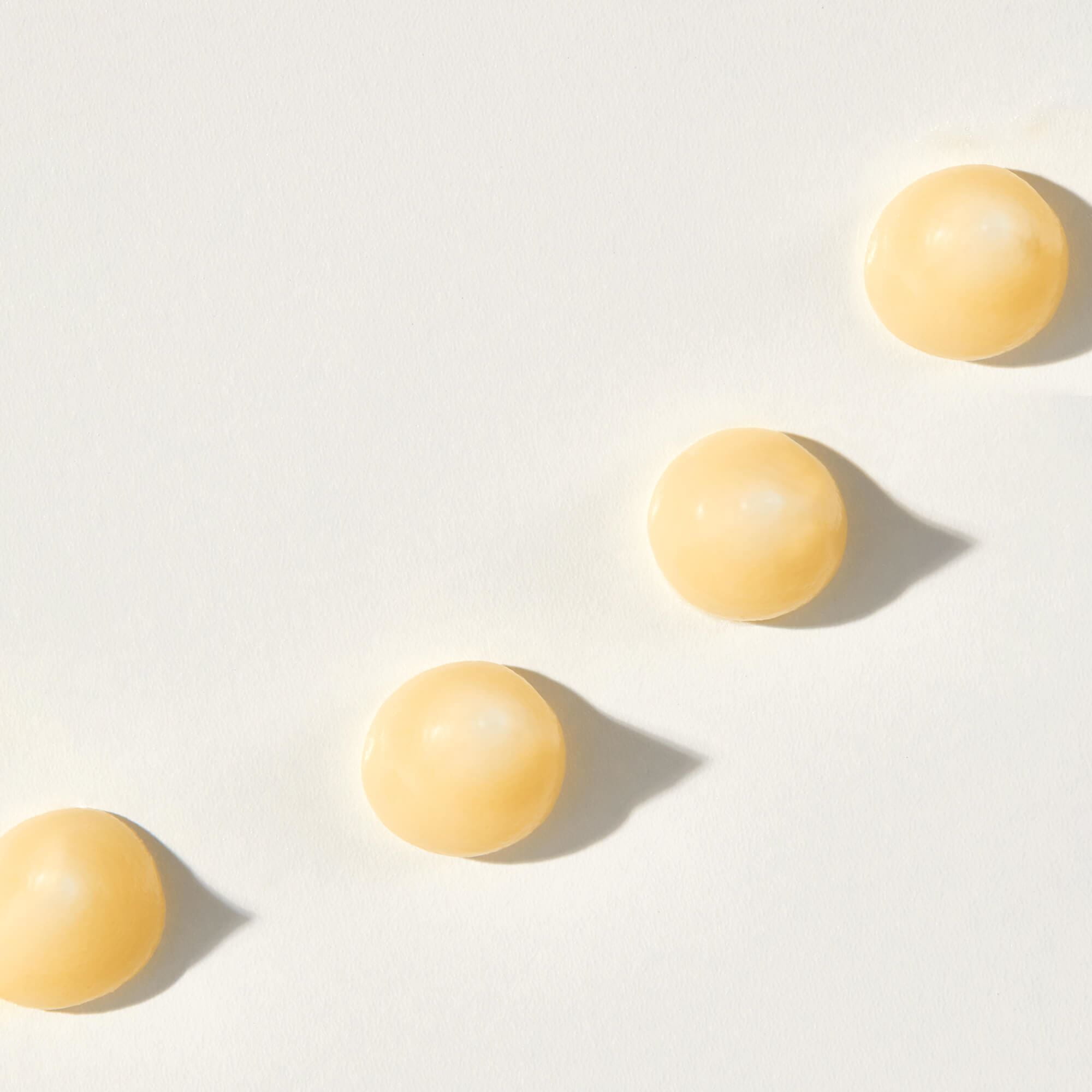 A closeup view of yellow coloured peptides against a white background.