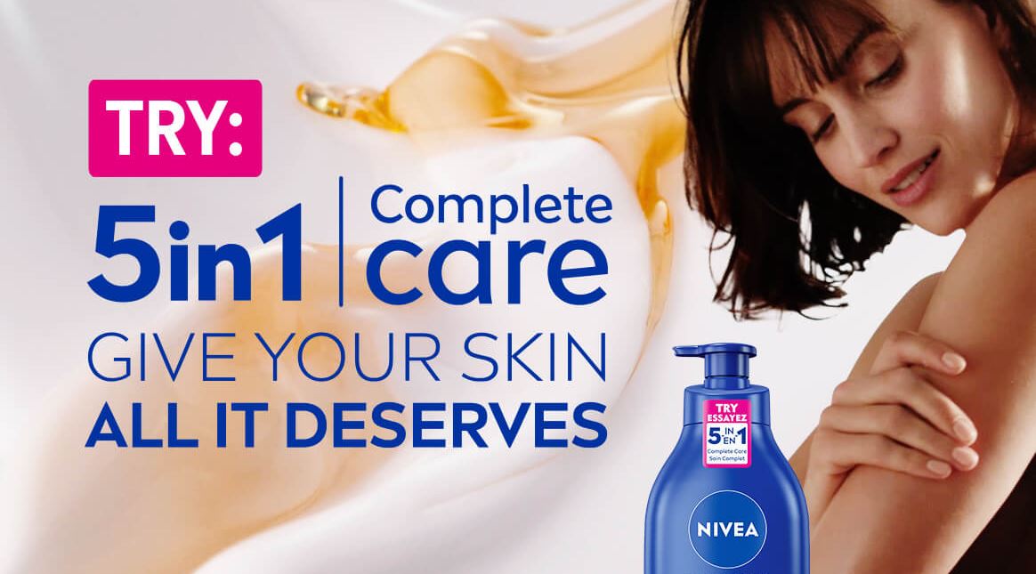 View of a female model holding her left arm with a NIVEA 5-in-1 Complete Care Nourishing Body Milk product and product text displayed to the left. 