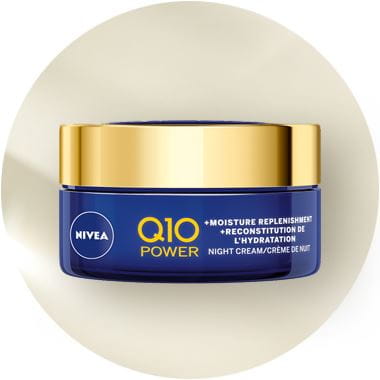 View of a Nivea Q10 Power moisture replenishment night cream face product against a beige background.