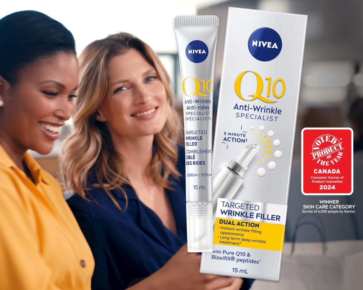 View of two female models smiling while holding a cell phone with the Nivea Q10 Anti Wrinkle Specialist targeted wrinkle filler product placed over top a blue background. 