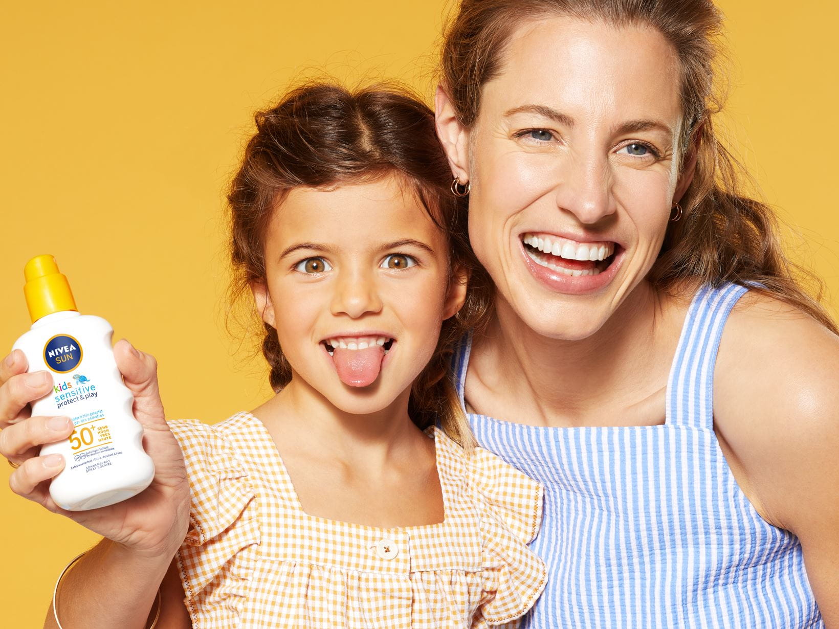 Femme et fillette posant avec le Spray Solaire Protect & Sensitive FPS 50+ NIVEA SUN Kids.