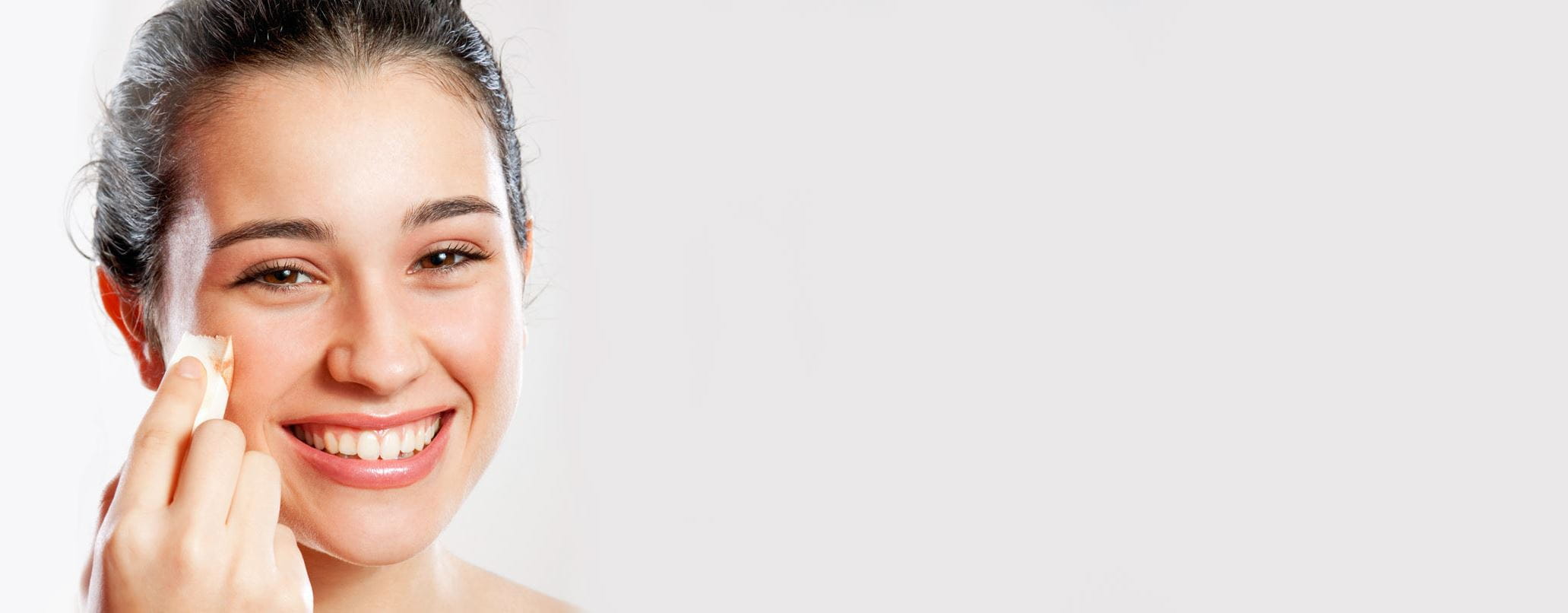 Frau trägt Foundation mit einem Kosmetikschwamm auf ihr Gesicht auf