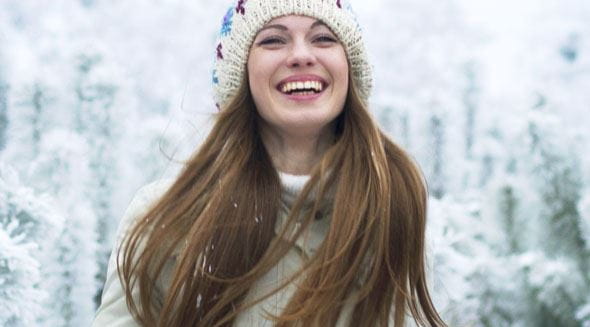 Frau steht im Schnee und lacht