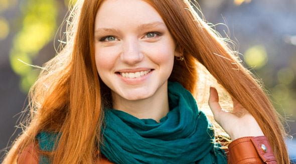 Frau mit roten Haaren lächelt in Kamera