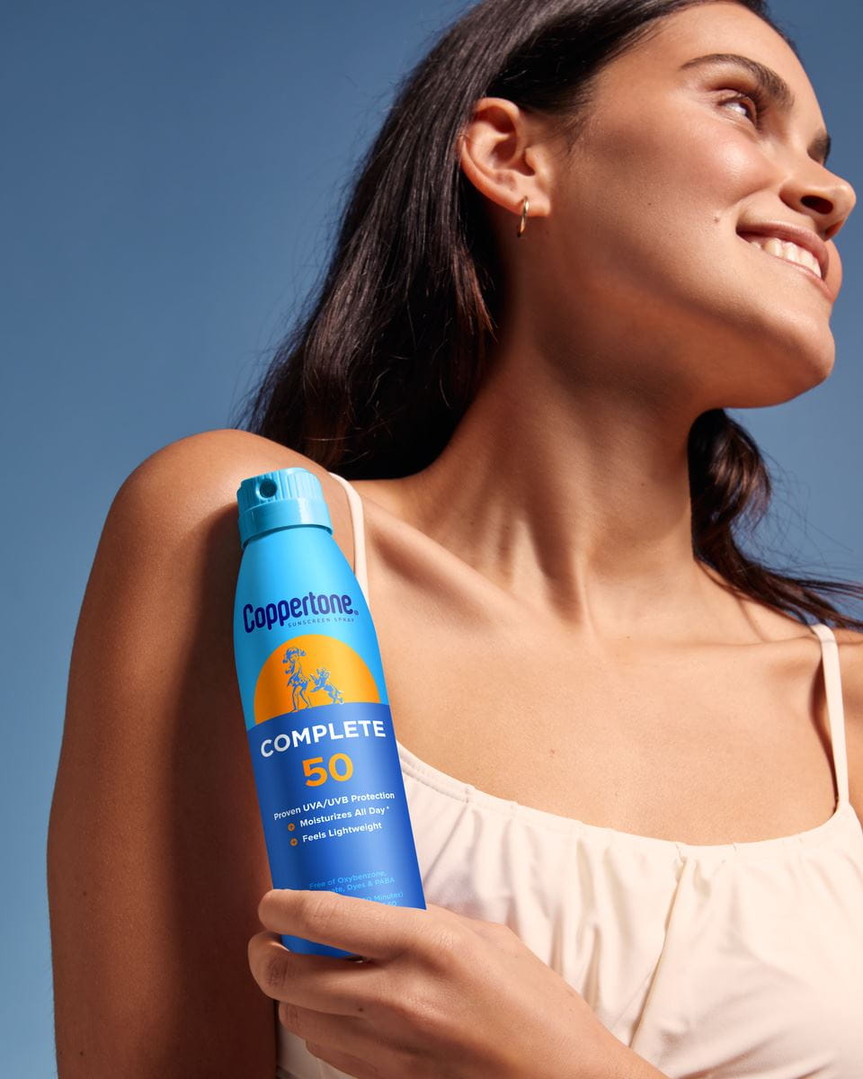 woman holding coppertone complete sunscreen spray