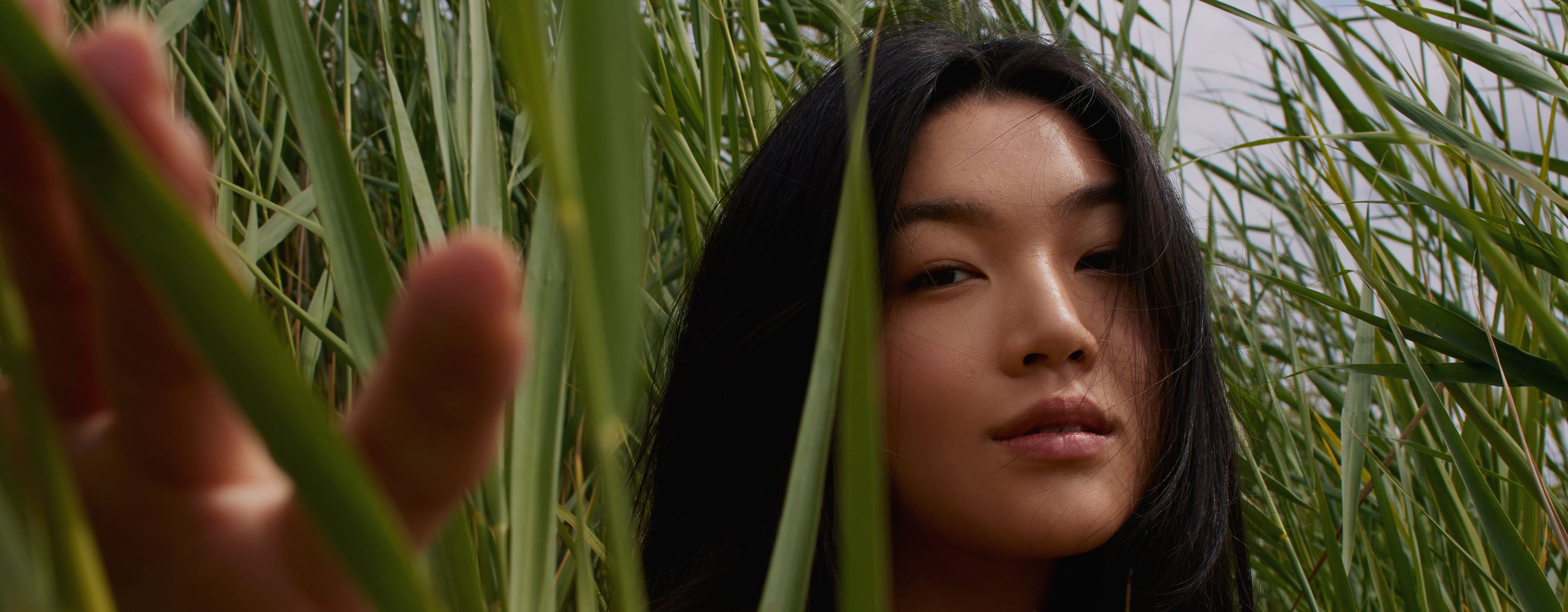 Asiatisches Mädchen steht auf einer grünen Wiese