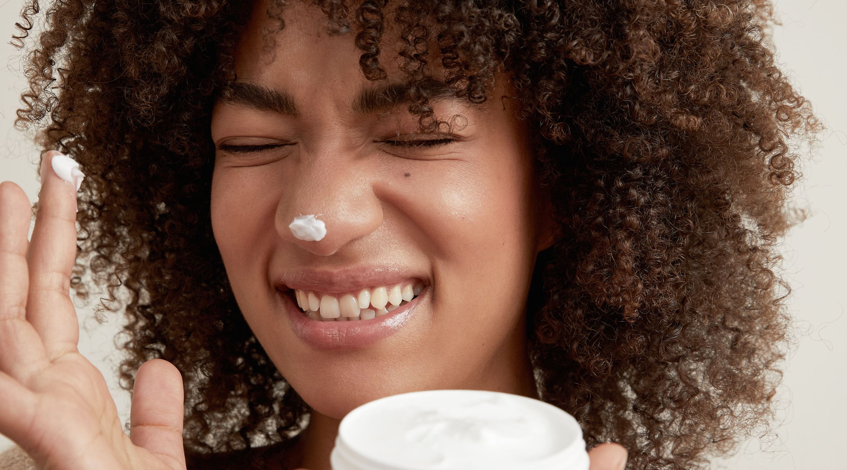 curly hair girl holding a Nivea face cream