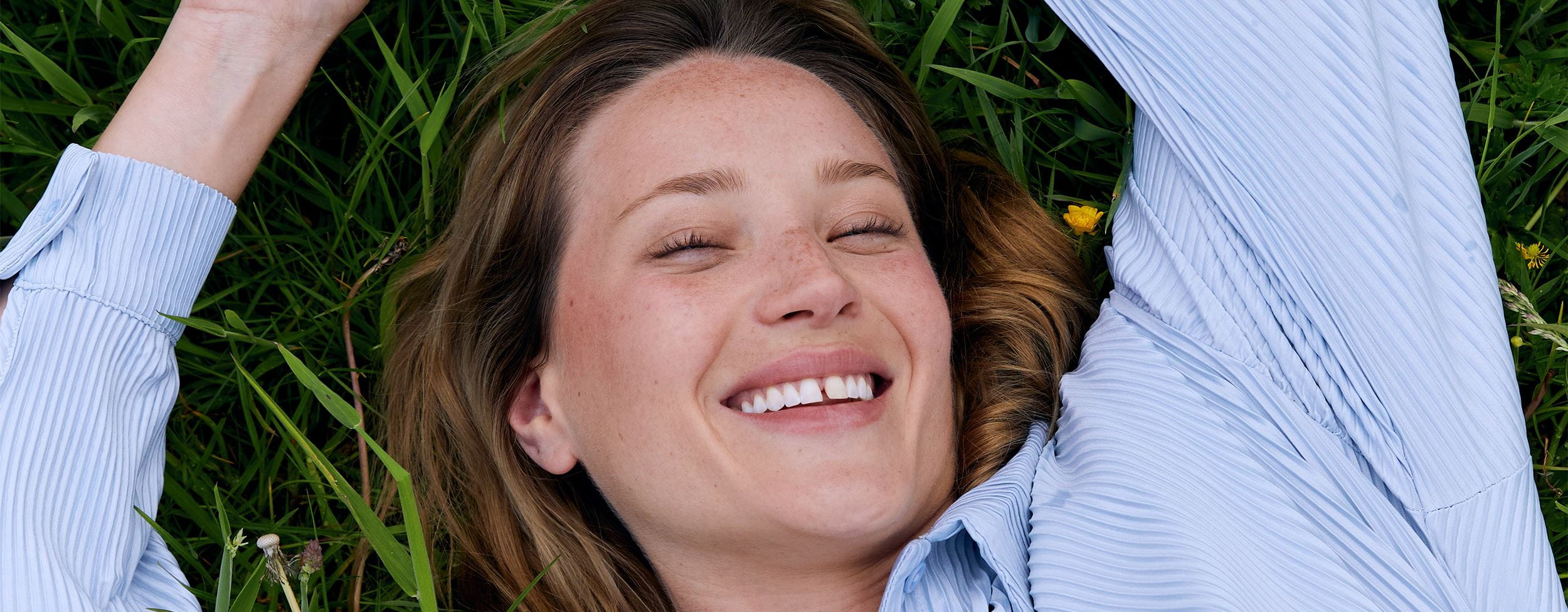 Frau liegt auf dem Gras und lächelt