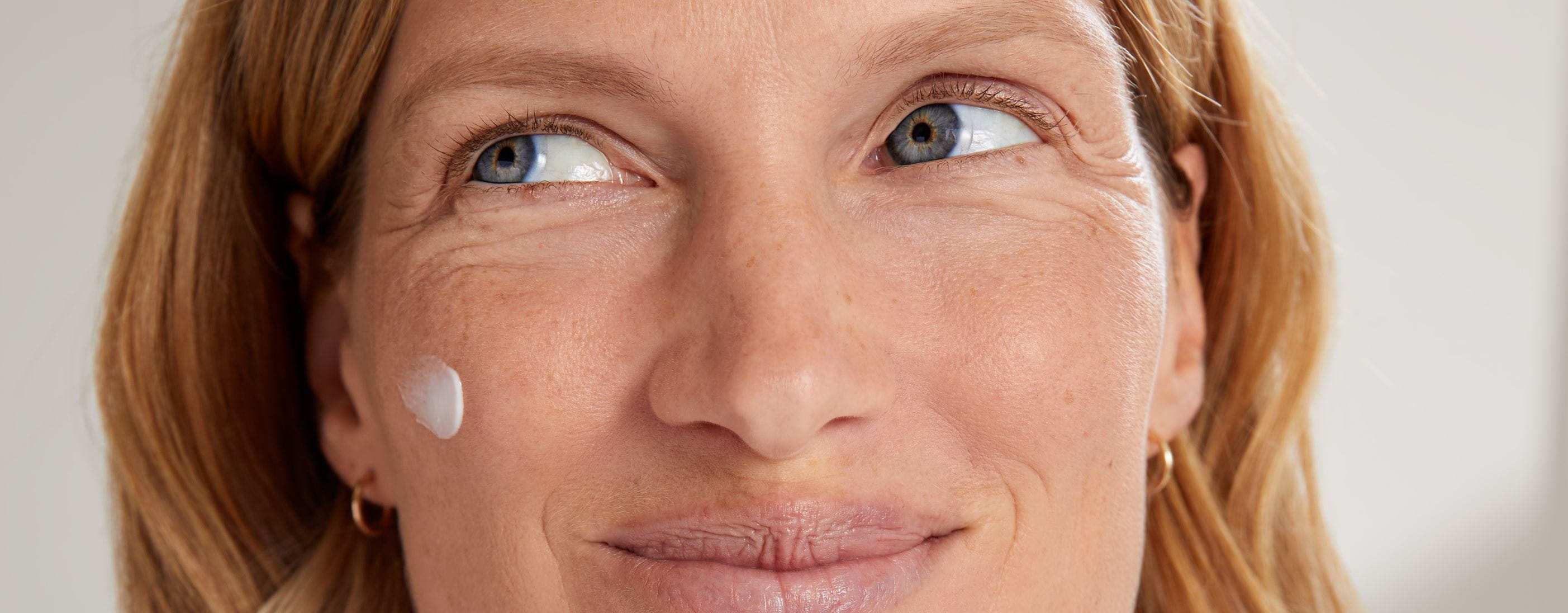 Mujer sosteniendo una crema facial antiarrugas Nivea Q10