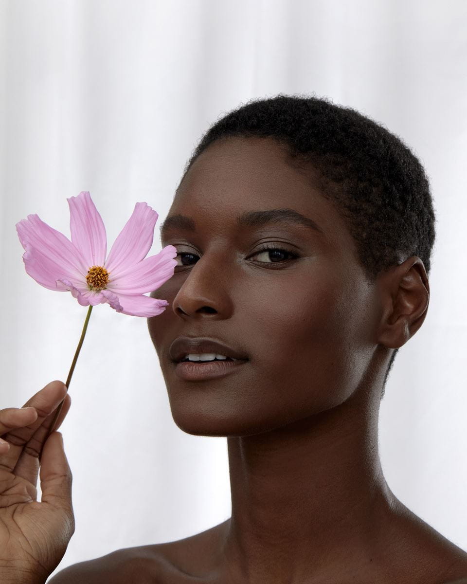 Μαύρο κορίτσι με ένα ροζ λουλούδι