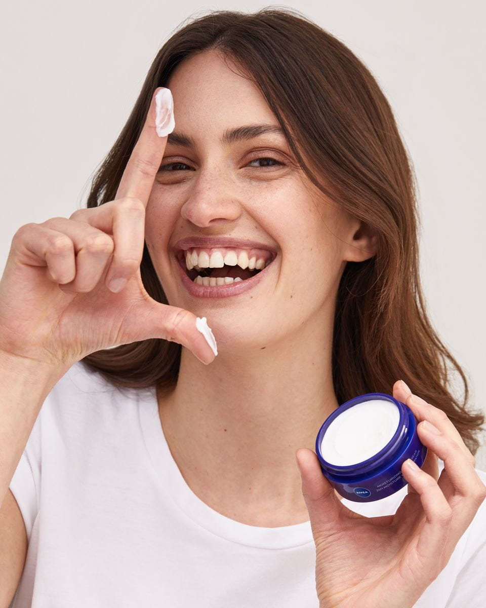 mulher aplicando creme facial Nivea